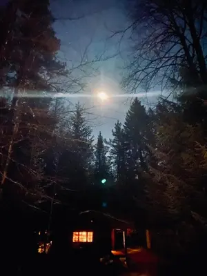 a full moon rising over a house at night at Skogshytte in Holmøyane