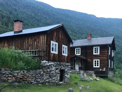 a large wooden house with a stone wall at Farm In The Heart Of Gudbrandsdalen in Kvam