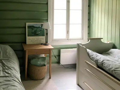 a bedroom with green walls and a bed and a table at Farm In The Heart Of Gudbrandsdalen in Kvam