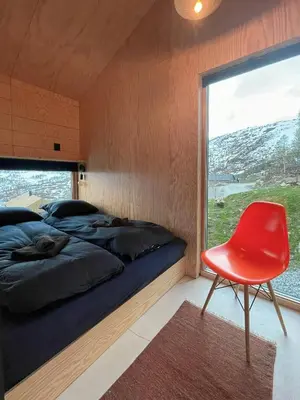 a bedroom with a bed and a red chair at Floating Dream Cabin Embraced By Nature in Sogndal