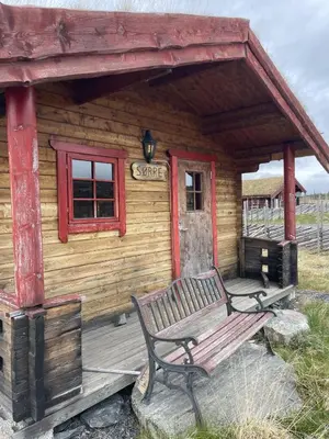 a wooden cabin with a bench in front of it at Syndinstøga in Ryfoss