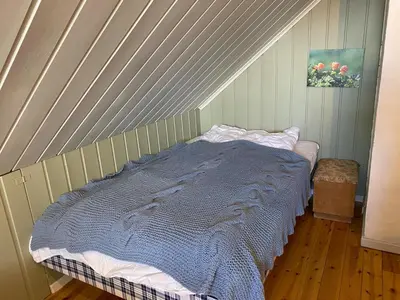 a bed with a blue comforter in a room at Huset Utsikten på Langsjøvolden gård in Tolga