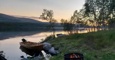 a boat sitting on the side of a lake at Huset Utsikten på Langsjøvolden gård in Tolga