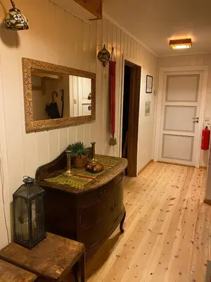a room with a wooden floor and a mirror at Huset Utsikten på Langsjøvolden gård in Tolga