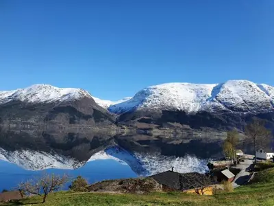 a reflection of a mountain in a body of water at Hardanger Fjord Living in Vossevangen