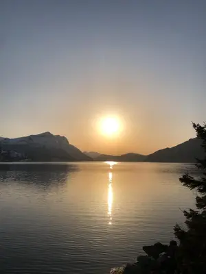 a sunset on a lake with mountains in the background at Charming farmhouse with jacuzzi and patio in Stryn