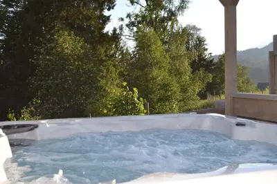 a jacuzzi tub in a yard with trees at Charming farmhouse with jacuzzi and patio in Stryn