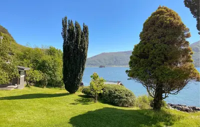 a garden with trees and a lake in the background at Stunning Apartment In Selje With Wifi in Selje