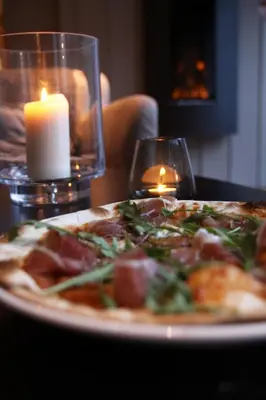a pizza sitting on a table next to a candle at Haukeli Hotel in Haukeligrend