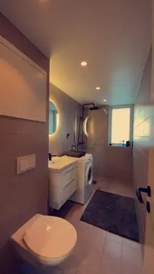 a bathroom with a toilet a sink and a microwave at Penthouse apartment with sauna, balcony and free coffe in Bergen