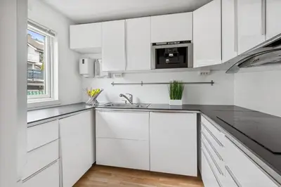 a white kitchen with white cabinets and a sink at Bønes in Bergen