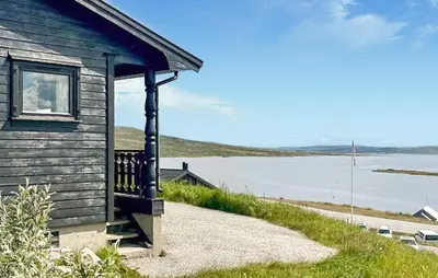a building with a porch and a body of water at Awesome Home In Vøringsfoss With Sauna in Maurset