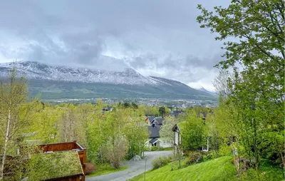 a snow covered mountain in the distance with a town and trees at 2 Bedroom Lovely Home In Oppdal in Oppdal
