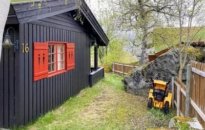 a yellow tractor parked next to a black building at 2 Bedroom Lovely Home In Oppdal in Oppdal