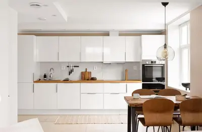 a kitchen with white cabinets and a table with chairs at Sentral leilighet, Bergen in Bergen