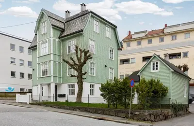 a green and white house on the side of a street at Sentral leilighet, Bergen in Bergen