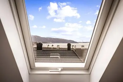 a window in a room with a view of the beach at Bright Top-Floor Apartment with Sea View in Bergen