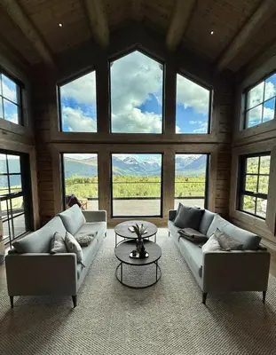 a living room with couches and a table and windows at Exclusive Fjord Lodge with Private Jacuzzi and Epic Views in Lii