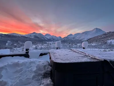 a winter sunset with snow covered mountains in the background at Exclusive Fjord Lodge with Private Jacuzzi and Epic Views in Lii