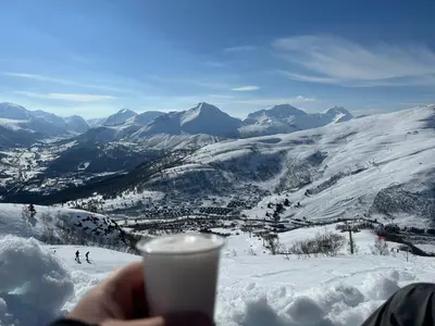 a person holding a cup of coffee on a snowy mountain at Exclusive Fjord Lodge with Private Jacuzzi and Epic Views in Lii