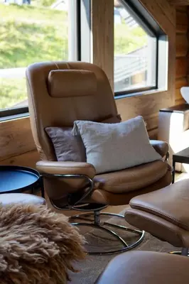 a brown chair sitting in front of a window at Exclusive Fjord Lodge with Private Jacuzzi and Epic Views in Lii