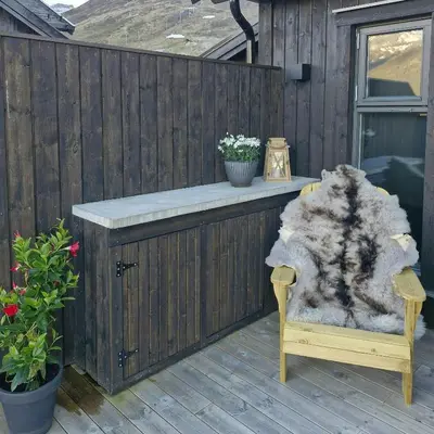 a wooden deck with a bench and a table with flowers at Mountain Cabin With Sauna In Sunnmørsalpane in Brunstad