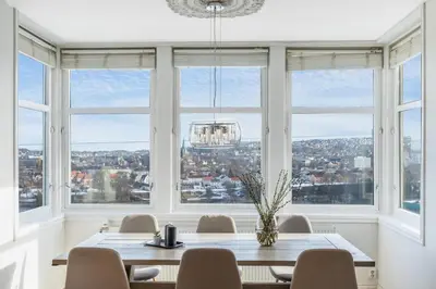 a dining room with a table and chairs and windows at Stor 3-roms leilighet med utsikt in Trondheim
