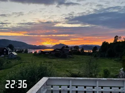 a sunset over a field with a fence in a field at Summer villa with heated pool 50 min from Bergen