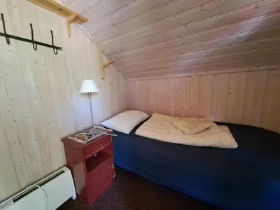 a small bedroom with a bed in a wooden wall at xxx in Ryfoss