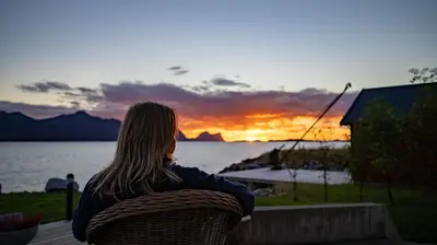 a woman sitting on a bench watching the sunset at Posthuset Expedition Lodge in Lii
