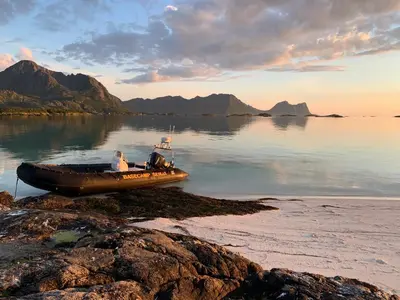 a boat sitting on the shore of a body of water at Posthuset Expedition Lodge in Lii