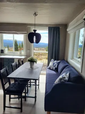 a living room with a blue couch and a table at Koselig liten fjellhytte i flott turterreng både sommer og vinter in Hovda
