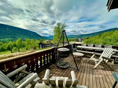 a deck with a bbq and chairs and a grill at Stylish log cabin in Hafjell with view & sauna in Hafjell