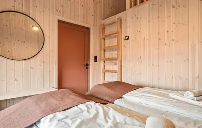 a bedroom with wooden walls and a bed with a mirror at 4 Bedroom Awesome Home In Vøringsfoss in Maurset