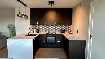 a kitchen with black cabinets and white counter tops at Apartment Suite in Os in Osøyro