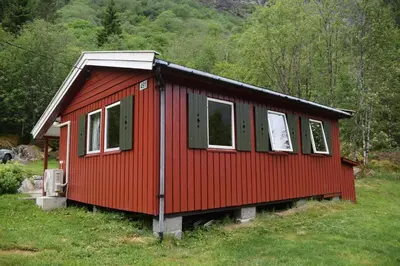 a red house in the middle of a field at Skogshytte in Bjordal