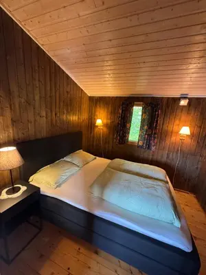 a large bed in a room with wooden walls at Lakeside cabin in Snofugl