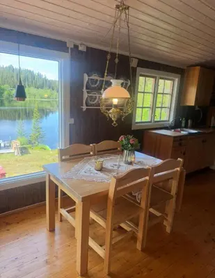a dining room table with chairs and a view of a lake at Lakeside cabin in Snofugl
