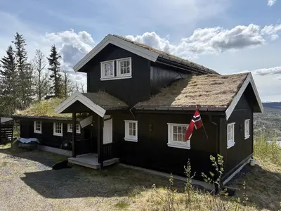 a black house with a grass roof at Modernized Log Cabin With Views Of The Mountains in Ron