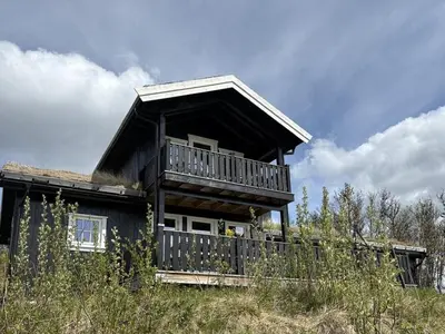 a large wooden house with a balcony on a hill at Modernized Log Cabin With Views Of The Mountains in Ron