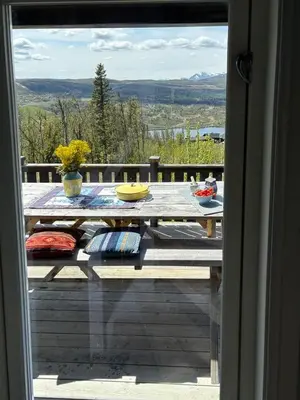 a table on a deck with a view from a window at Modernized Log Cabin With Views Of The Mountains in Ron