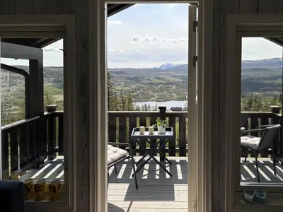 a porch with a table and a view of the mountains at Modernized Log Cabin With Views Of The Mountains in Ron