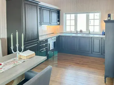 a kitchen with dark blue cabinets and a table with a counter at Family-Friendly Mountain Cabin In Haukeli in Nesland
