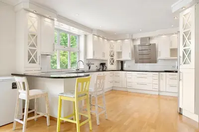 a kitchen with white cabinets and yellow bar stools at 4-Bedroom Apartment with Balcony in Odda