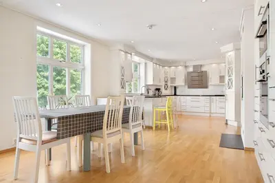a white kitchen with a table and chairs at 4-Bedroom Apartment with Balcony in Odda