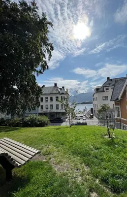 a park bench sitting in the grass near some buildings at Attractive and central apartment in Ålesund