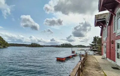 a dock on a lake next to a red building at Cozy Home In Lepsøy With House Sea View in Lepsøy