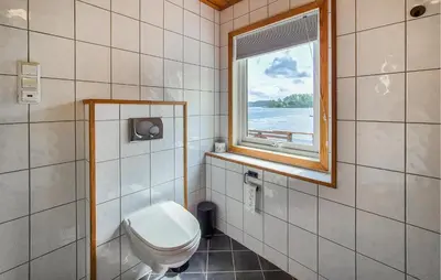 a bathroom with a toilet and a window at Cozy Home In Lepsøy With House Sea View in Lepsøy