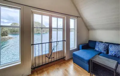 a living room with a blue couch and large windows at Cozy Home In Lepsøy With House Sea View in Lepsøy