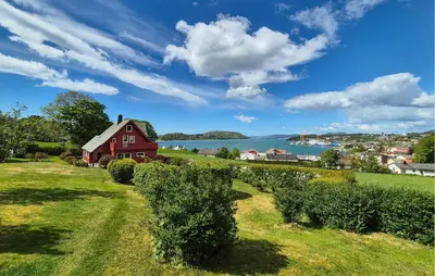 a red barn on a hill next to the water at Awesome Home In Fitjar With Wifi in Fitjar